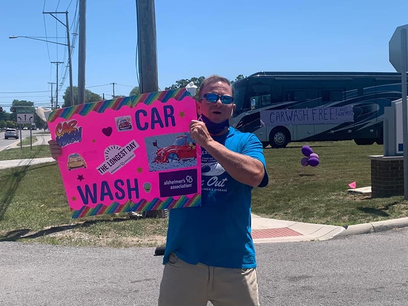 Charter CEO Keven Bennema holds car wash sign to fundraise for The Longest Day.